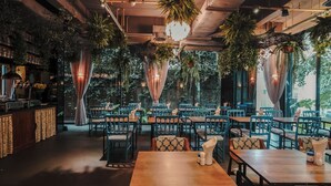 An indoor restaurant with wooden tables and chairs, hanging plants, and a bar area. - Sugar Marina Resort -Surf- Kata Beach (Karon)
