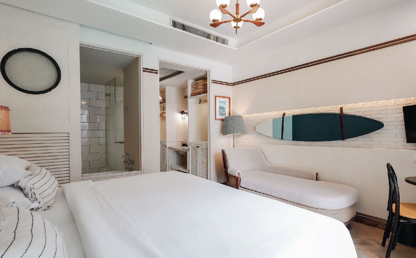 Un dormitorio con cama, sofá, televisor y una tabla de surf en la pared.