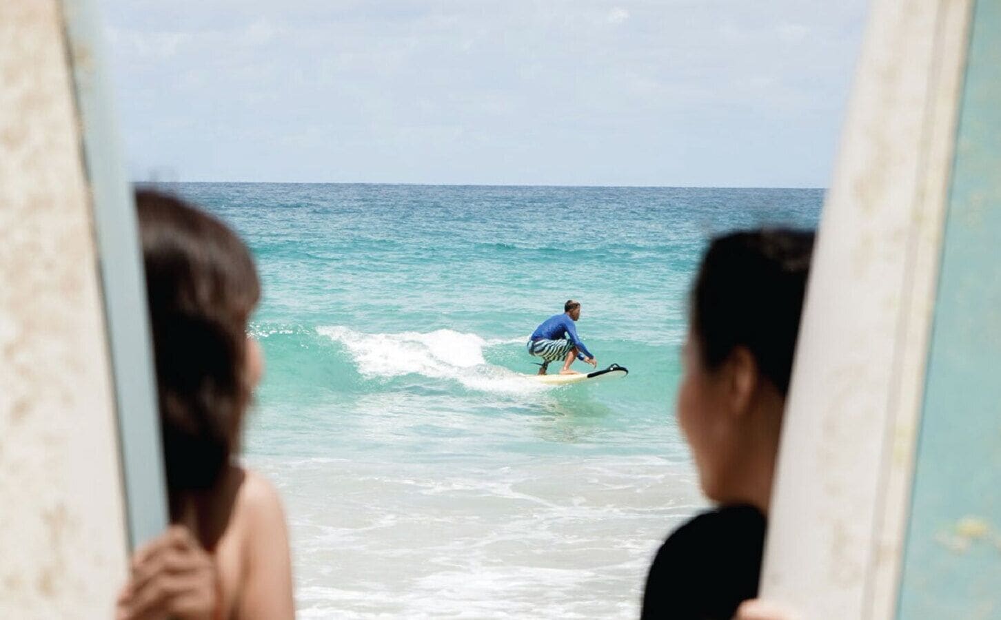 A person surfing on a wave, viewed from behind a window.