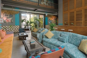 A modern living room with a sofa, coffee table, and chairs, featuring a large window with a view of greenery.