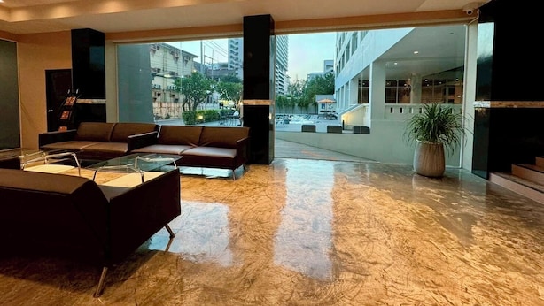 Een ruime lobby met een modern design, voorzien van een zithoek met banken en een glazen bijzettafeltje. Grote ramen bieden uitzicht op de stad.