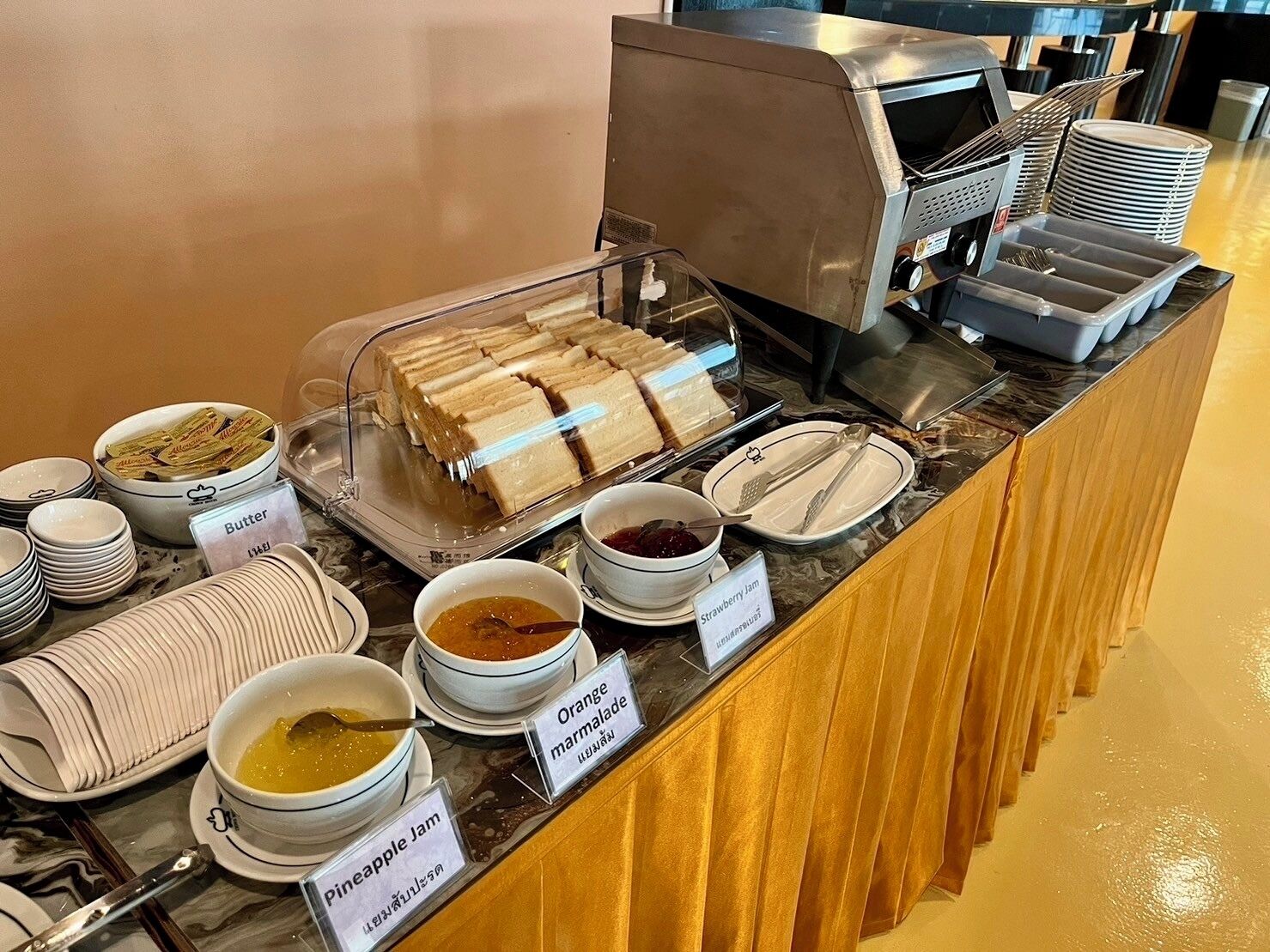 A buffet with sandwiches, bowls of jam, marmalade, and pineapple jam.