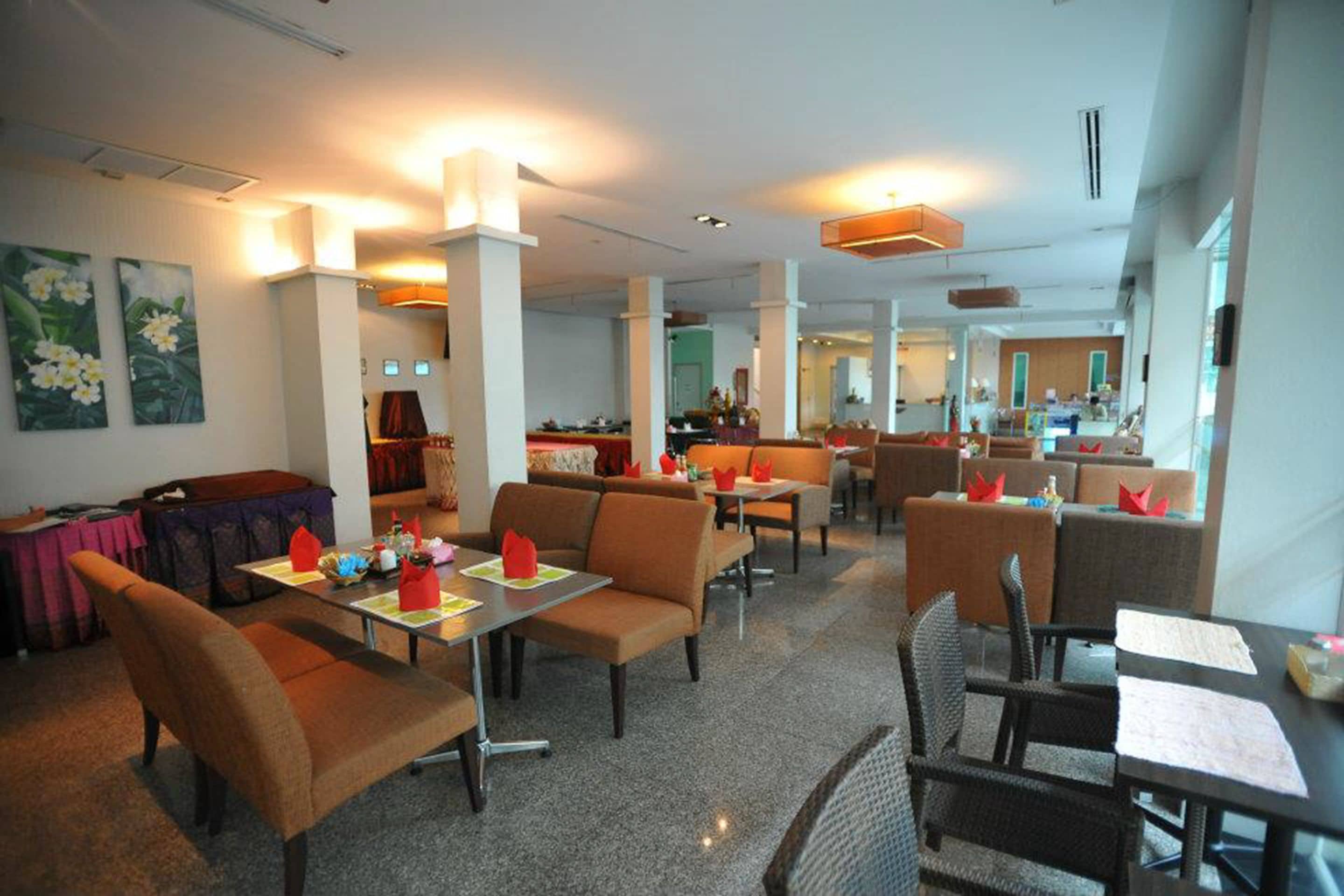 En rummelig hotellobby med flere siddeområder, herunder sofaer og borde, samt et centralt område med en disk.