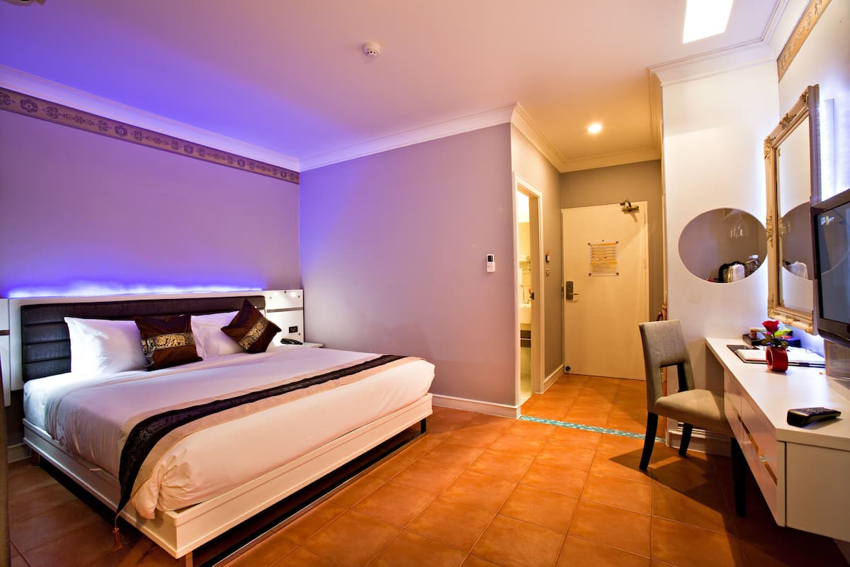 A hotel room with a bed, a desk, and a mirror.