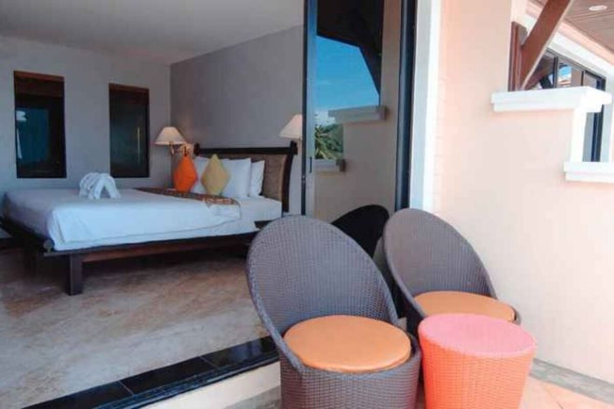 Una habitación de hotel con una cama, dos sillas, una mesita y una ventana.