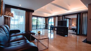 A spacious living area with a leather sofa, a coffee table, and a TV. There is a balcony with a view of the outdoors. - C&N Resort and Spa (Patong)