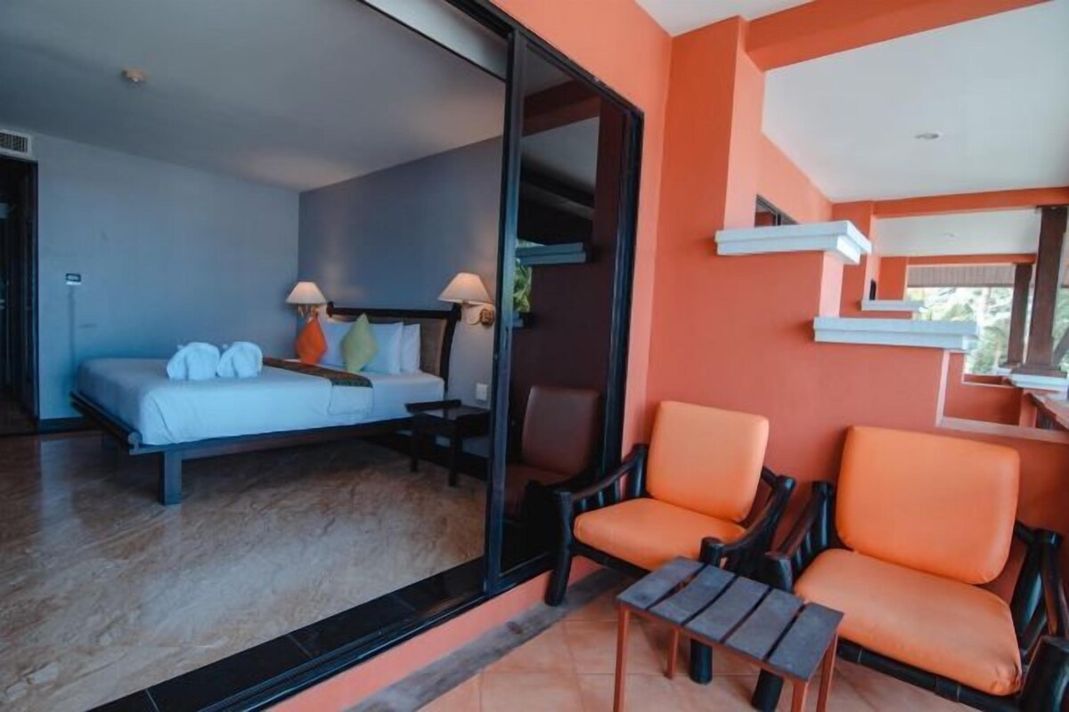 A bedroom with a bed, two chairs, and a small table.