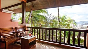 A wooden bench and table on a balcony with a view of tropical vegetation and a distant cityscape. - C&N Resort and Spa (Patong)