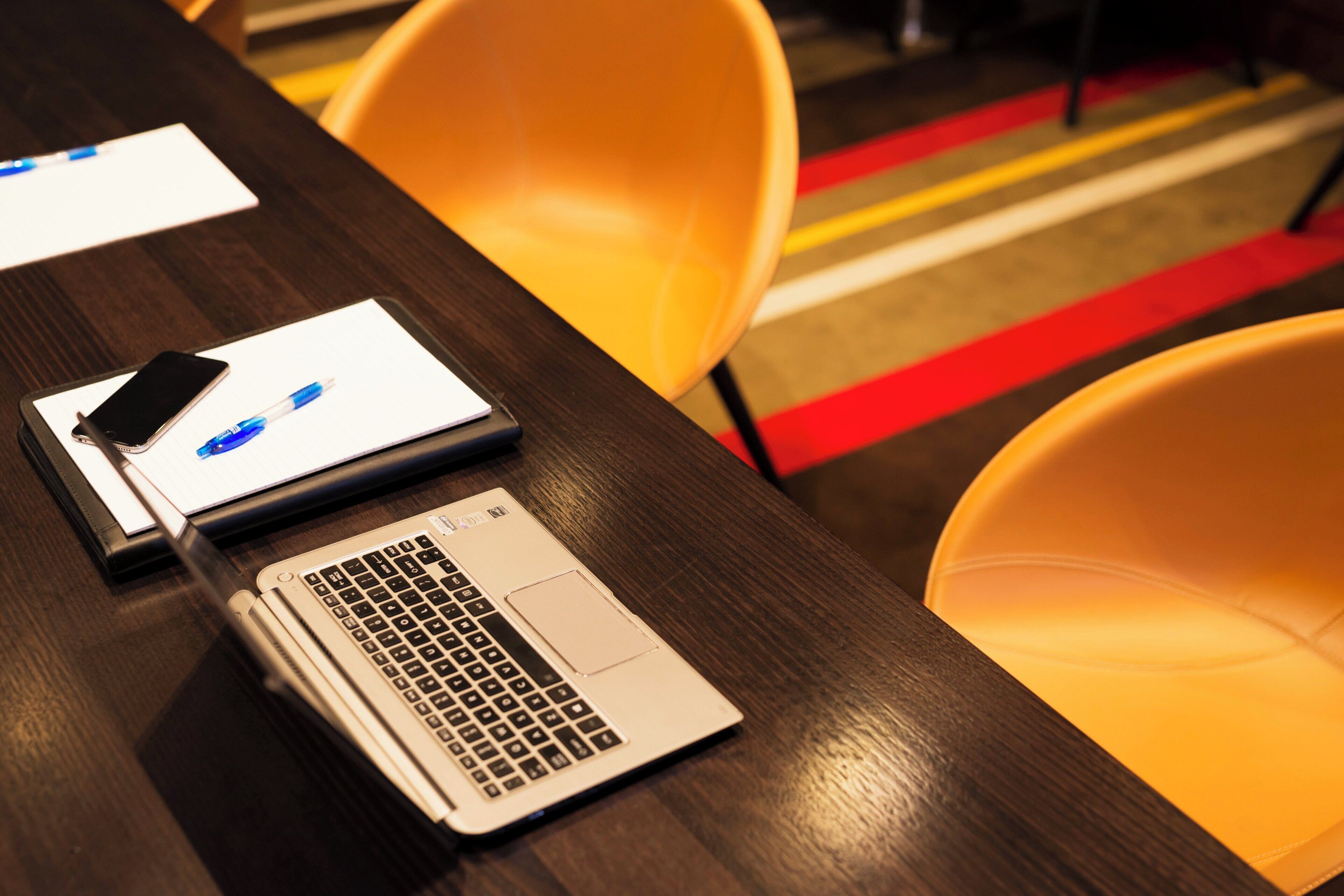A wooden table with a laptop and a smartphone on it.