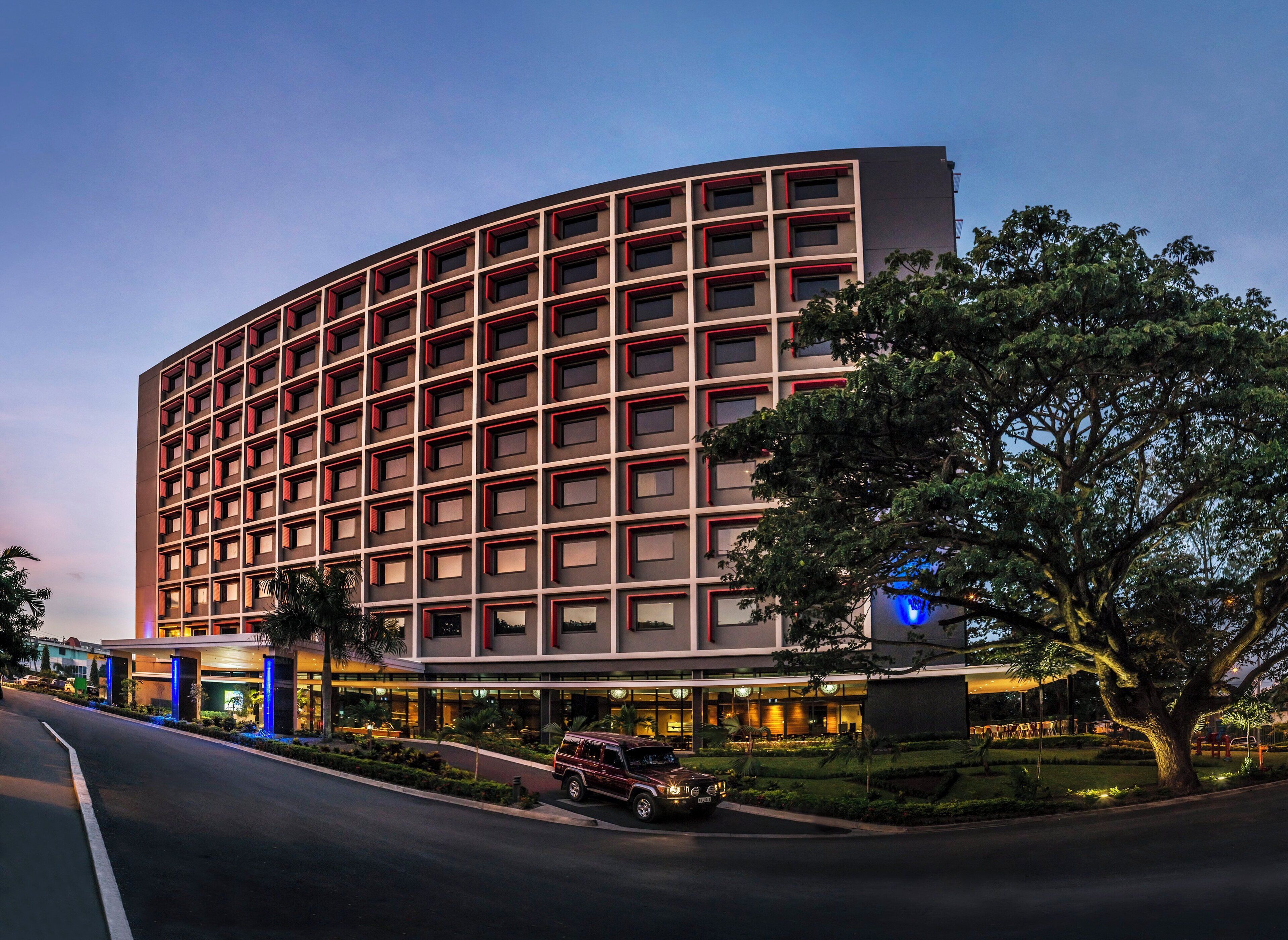 A multi-story hotel with a modern design, featuring a curved facade and a series of evenly spaced windows.