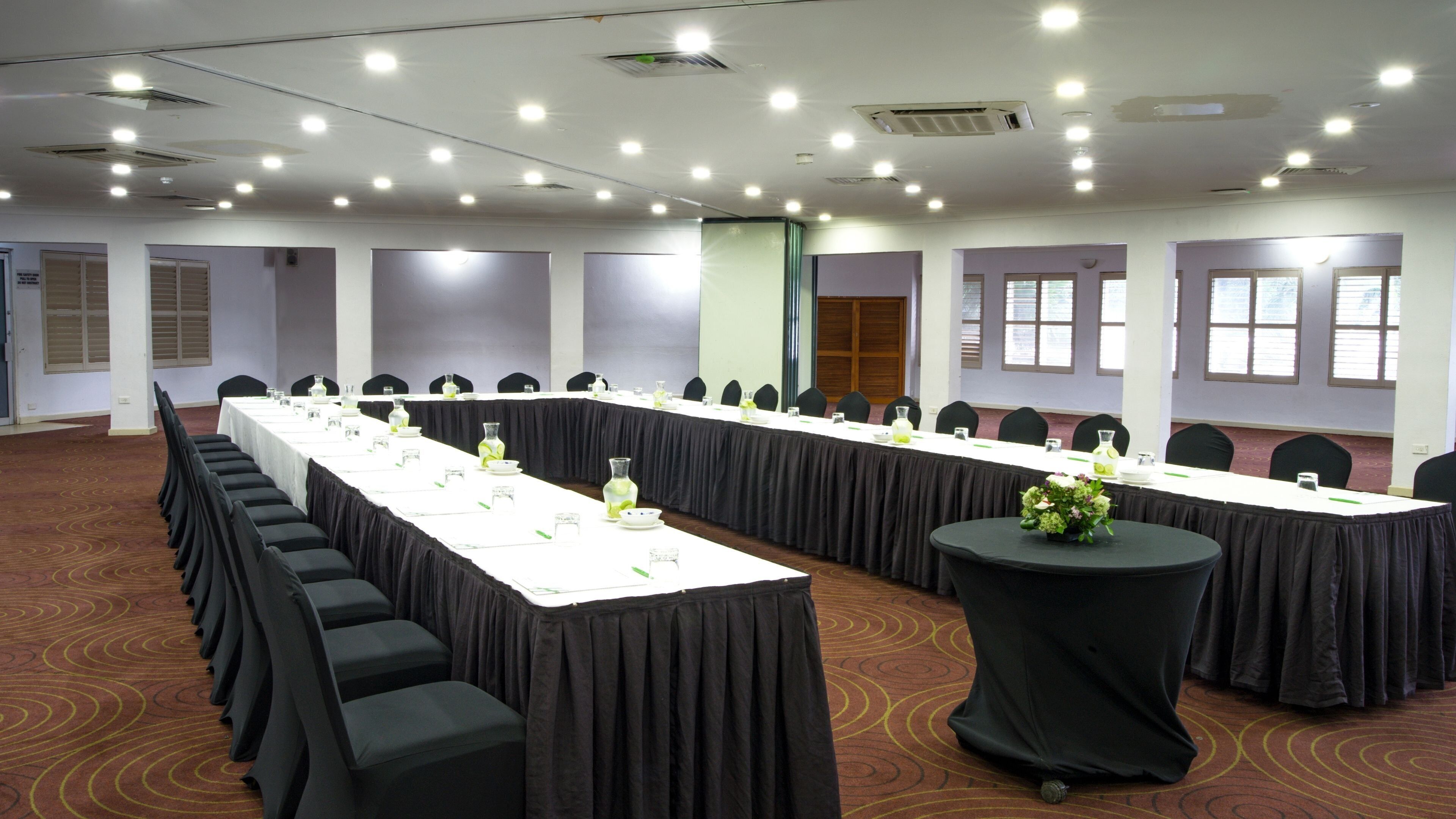 A conference room with a long table, chairs, and a smaller table with a vase.