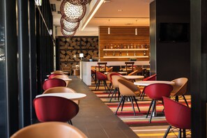 A modern hotel lobby with a long dining area, red chairs, and a bar with bottles. - Holiday Inn Express Port Moresby by IHG (Port Moresby)