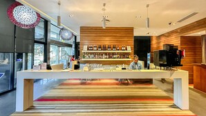 A modern bar area with a long counter, shelves with bottles, and a television. - Holiday Inn Express Port Moresby by IHG (Port Moresby)