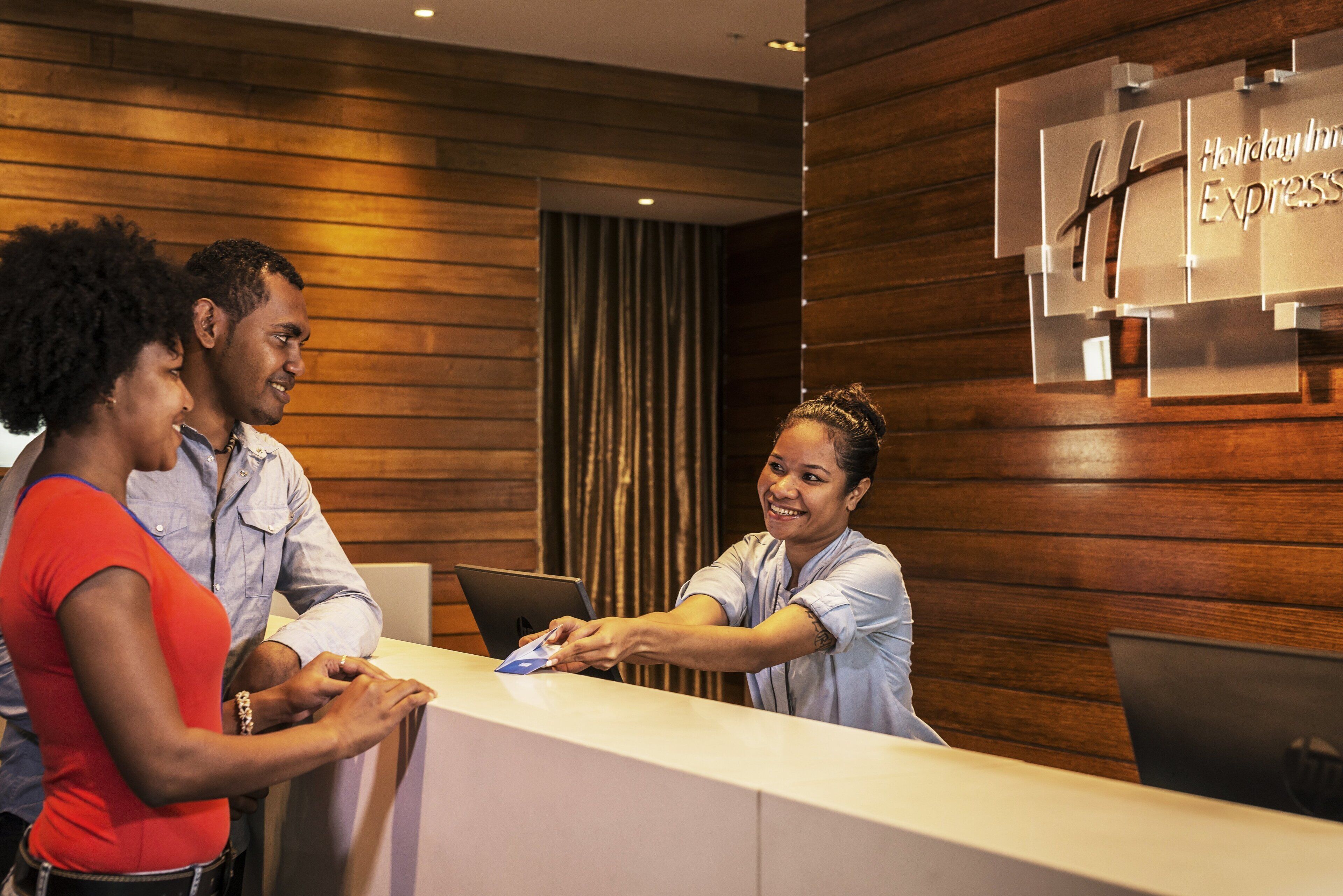A reception desk with a wooden panel wall and a sign indicating a Holiday Inn Express.
