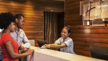 Un comptoir d’accueil avec un mur revêtu de panneaux en bois et une enseigne indiquant qu’il s’agit d’un Holiday Inn Express.