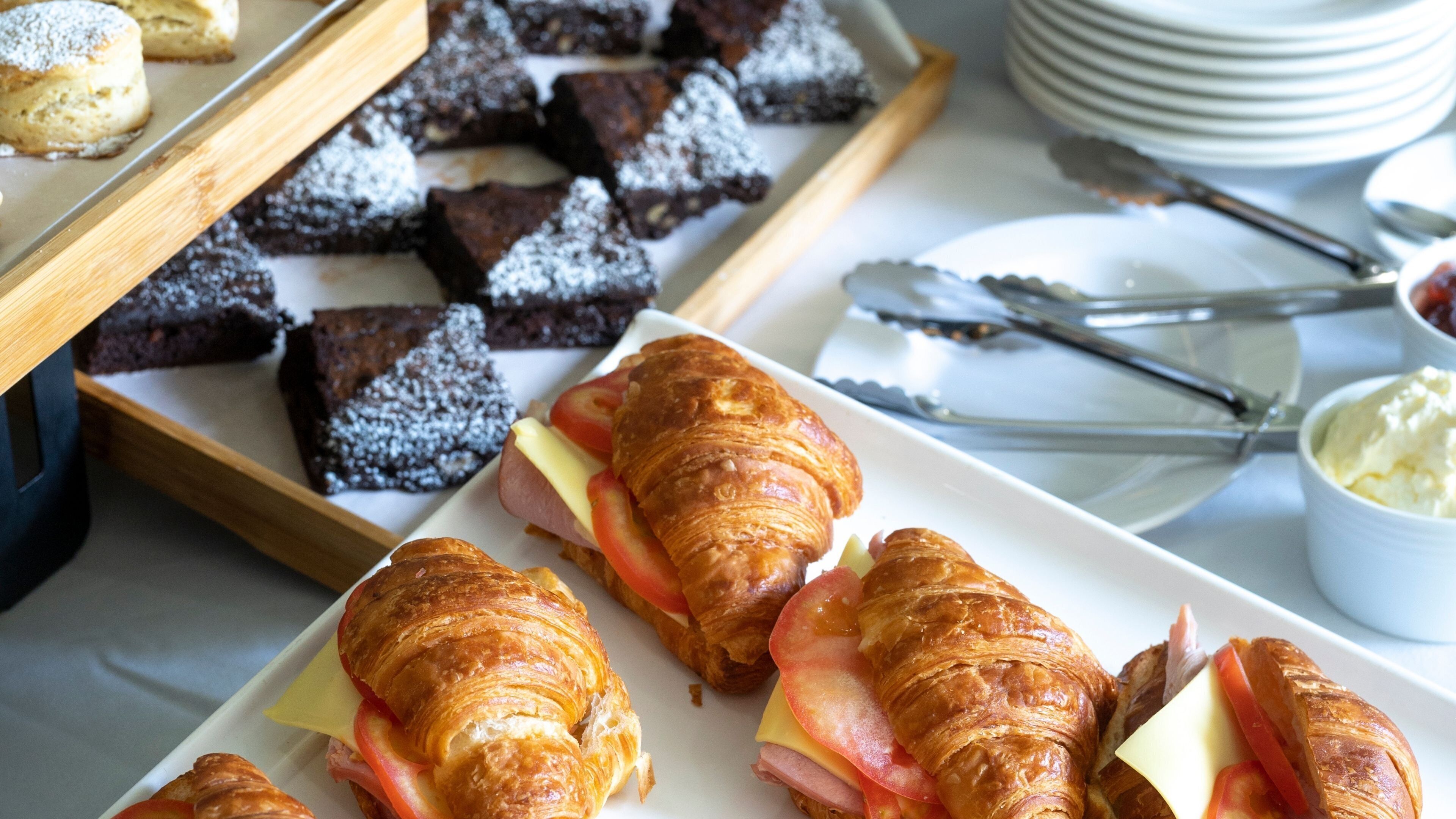 A breakfast buffet with croissants, sandwiches, and brownies.