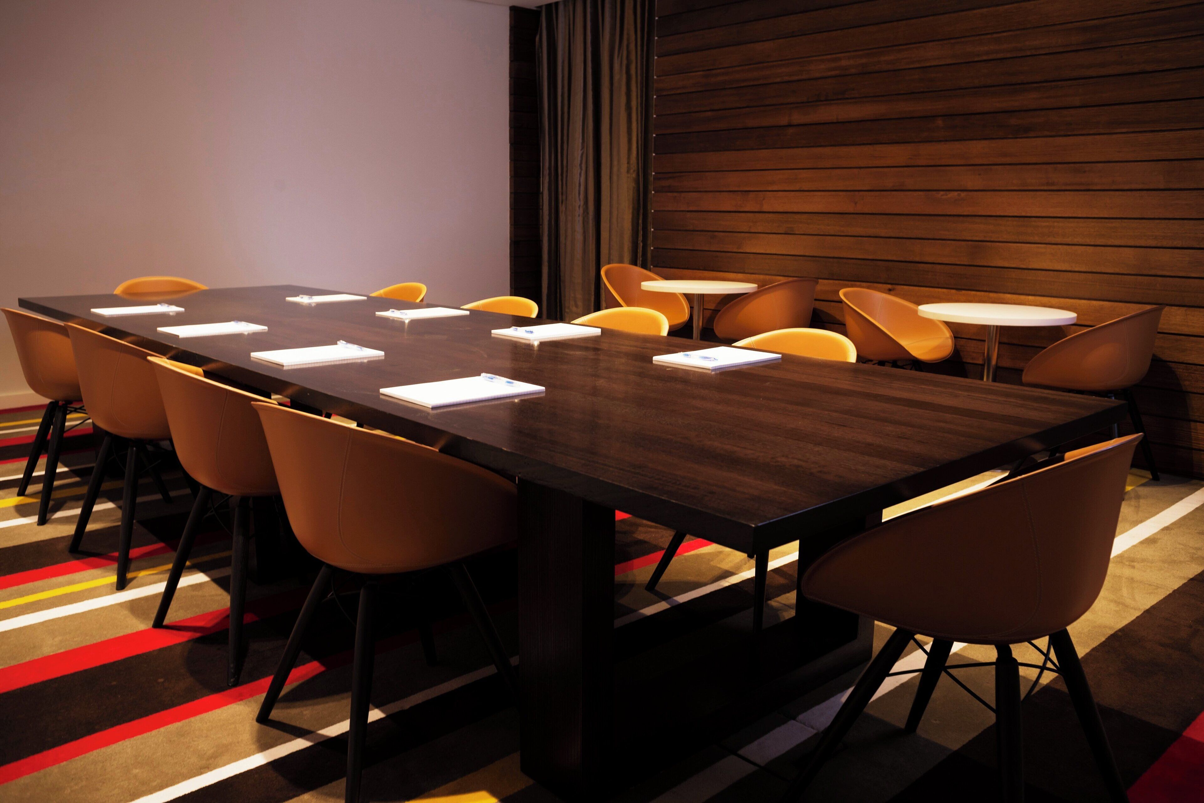 A conference room with a long table, multiple chairs, and a carpeted floor.