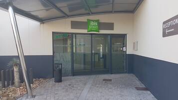 A hotel entrance with a reception area, a glass door, and a sign for 'ibis Styles Hotels'.