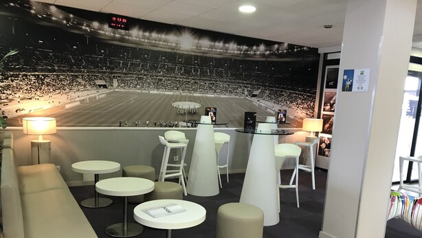 A modern bar area with white bar stools, round tables, and a seating area with a sofa. - ibis Styles Villeneuve sur Lot (Villeneuve-sur-Lot)