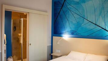 Een hotelkamer met een bed, een douche en een muur met een bladmotief.