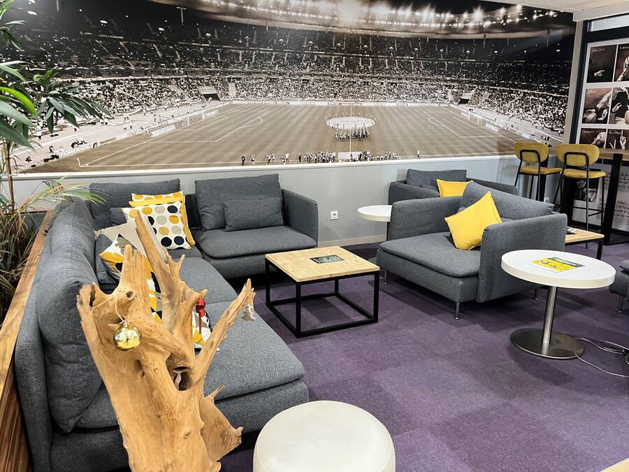 A modern lounge area with grey sofas, yellow cushions, and a large wooden tree sculpture.