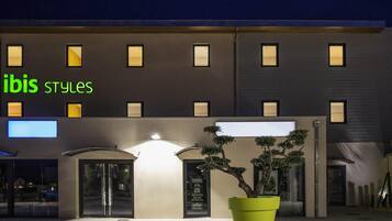 A building with a sign reading 'ibis styles' and a large potted plant in front.