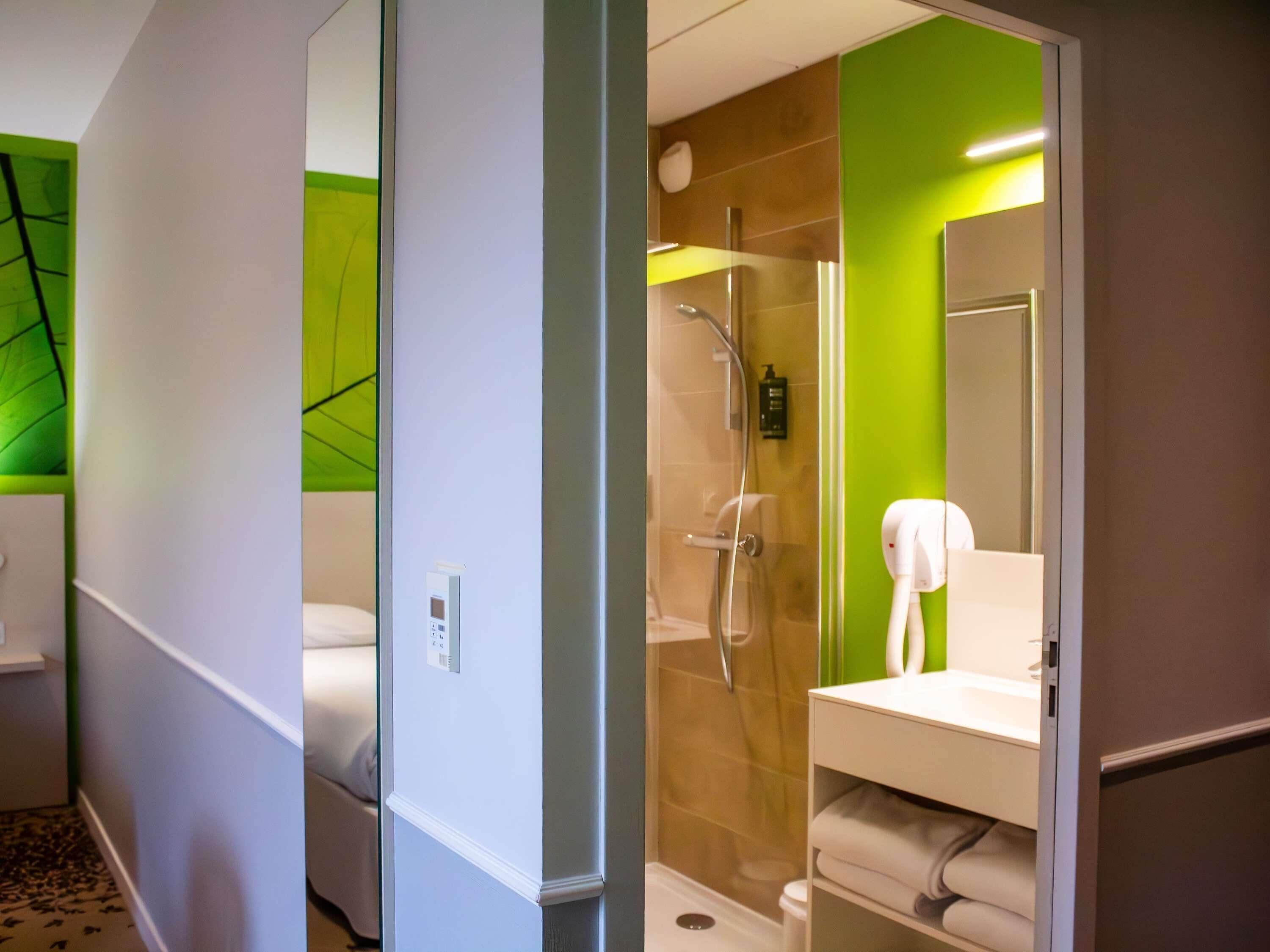 A hotel bathroom with a shower, a sink, and a mirror.