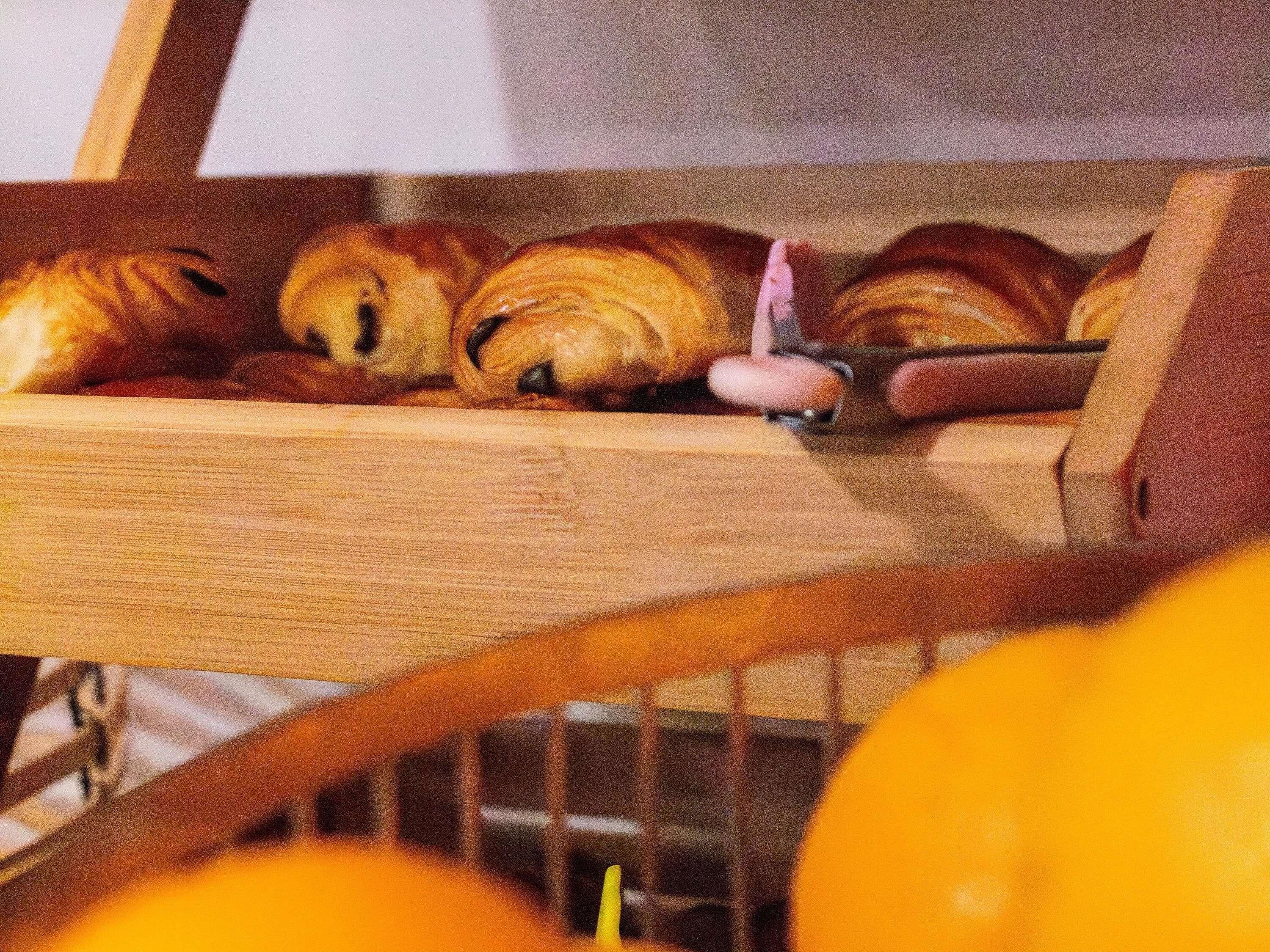 Uma cesta de madeira com croissants e um cortador de massa.
