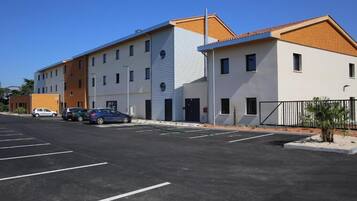 En moderne bygning med flere etager, en parkeringsplads og et par biler.