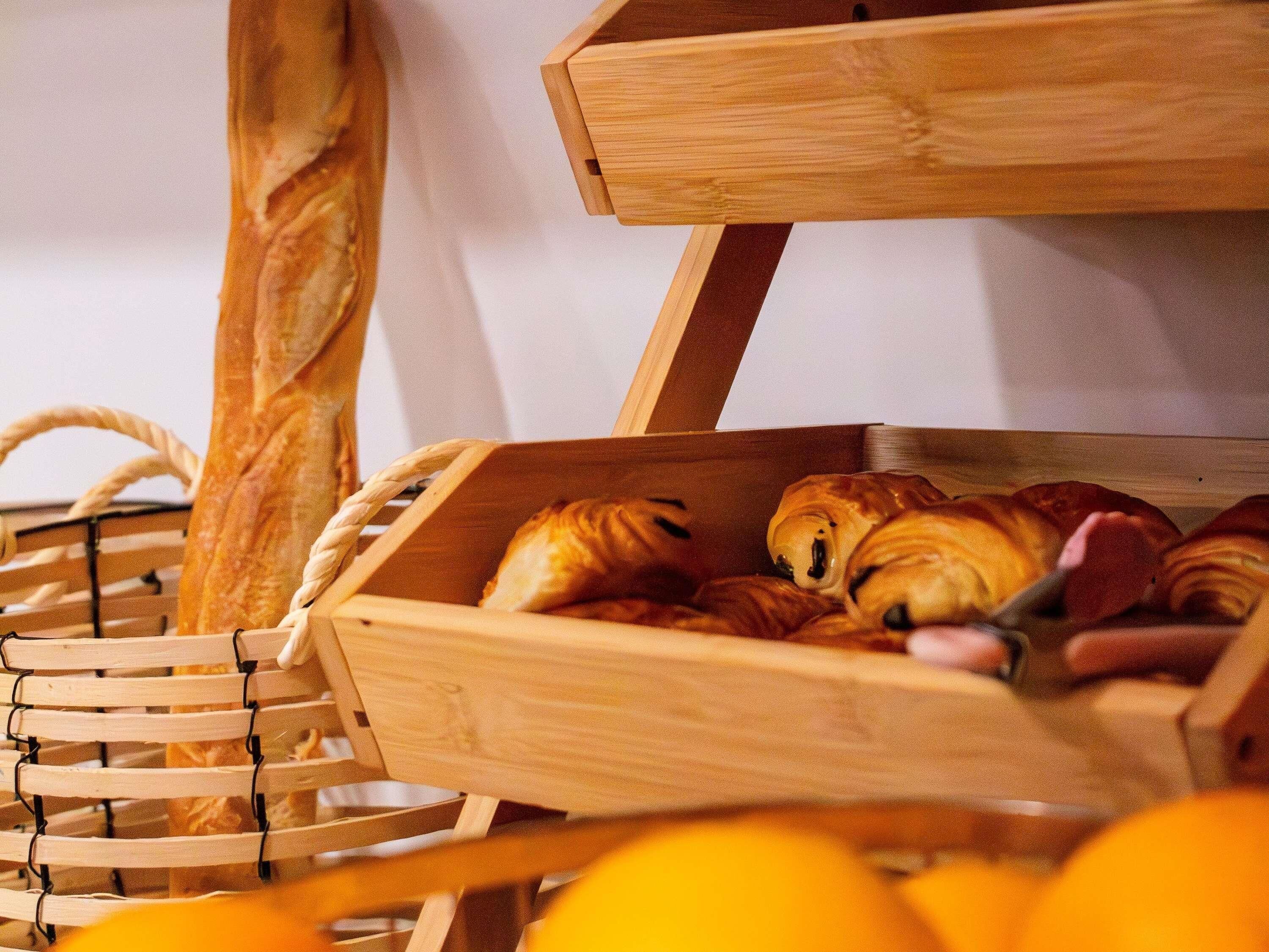 A wooden bread basket with croissants and a baguette.