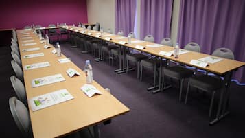 A conference room with a long table, chairs, nameplates, water bottles, and informational pamphlets.