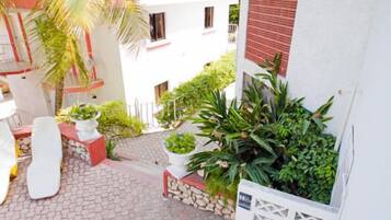 A courtyard with a white building, potted plants, and a white chair.