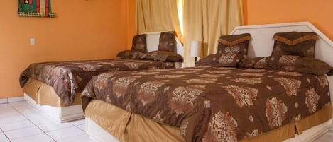 Habitación de hotel con dos camas, una mesita de noche, una lámpara y un adorno en la pared.