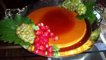 A dessert tray with a caramel flan, grapes, strawberries, and mint leaves.