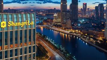A modern building with the sign "Shanghai" prominently displayed, surrounded by a river and high-rise buildings.