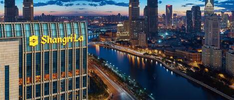 A modern building with the sign "Shanghai" prominently displayed, surrounded by a river and high-rise buildings.