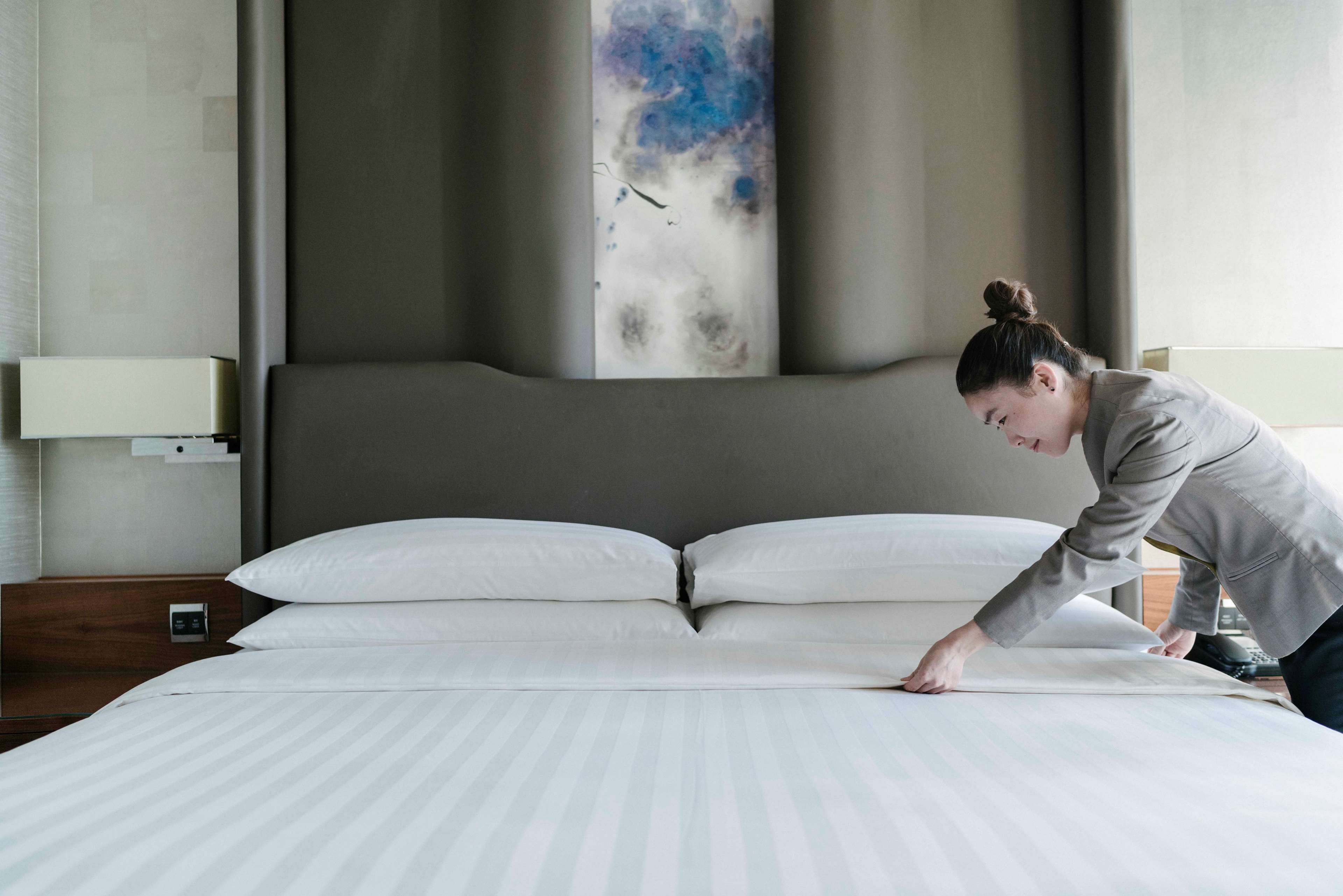 A neatly made bed with white linens in a modern hotel room.