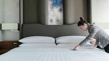 A neatly made bed with white linens in a modern hotel room.