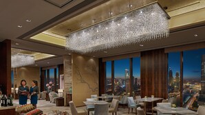 A luxurious hotel lobby with a high ceiling, chandeliers, a city view, a reception area, and a buffet with various desserts. - Shangri-La Tianjin (Tianjin)