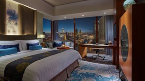 A hotel room with a large bed, a desk, and a view of a cityscape. - Shangri-La Tianjin (Tianjin)