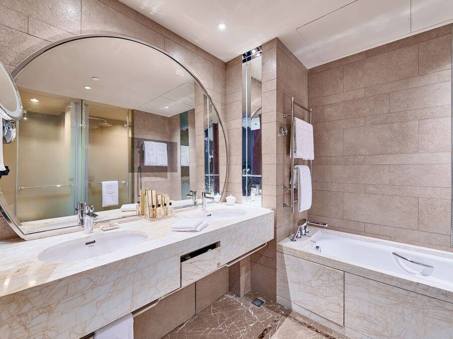 A modern bathroom with a large mirror, two sinks, a bathtub, and a glass shower enclosure.