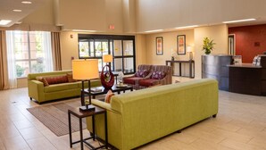 A spacious lobby with two green sofas, a coffee table, a lamp, and a reception desk. - Cotulla Express Inn (Cotulla)