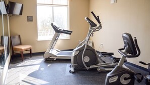 A fitness room with treadmills, an elliptical, and a chair. - Cotulla Express Inn (Cotulla)