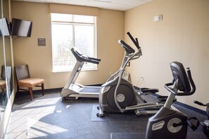 Un gimnasio con cintas de correr, una elíptica y una silla.