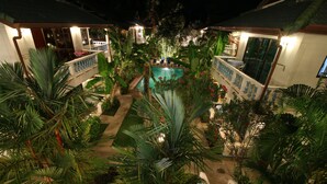 A pool surrounded by lush tropical plants, with a covered seating area and a staircase leading to a balcony. - Ya Nui Resort (Rawai)