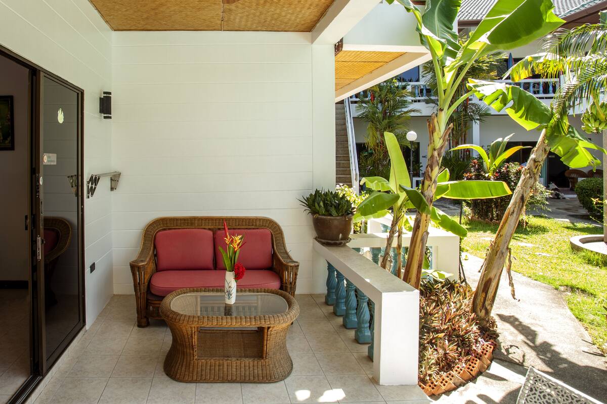 A room with a wicker sofa, a glass coffee table, and a ceiling fan.