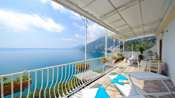 A balcony with a view of the sea, white railings, and outdoor furniture. - La Sorgente del Sole (Positano)