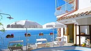 A poolside area with a view of the sea, outdoor furniture, and umbrellas. - La Sorgente del Sole (Positano)