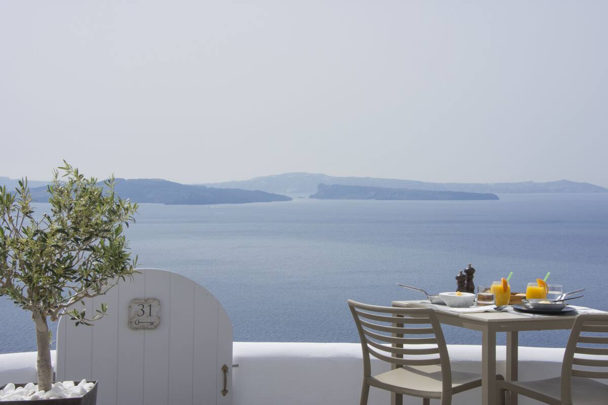 A table set for breakfast with a view of the sea and mountains.