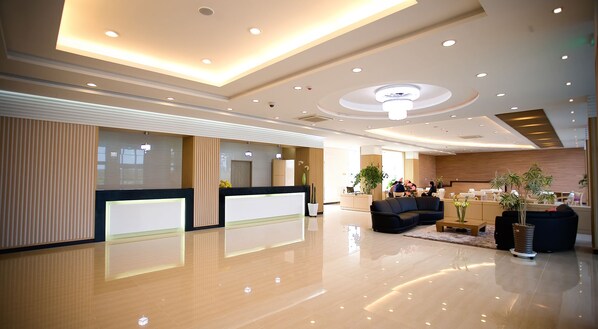 A modern hotel lobby with a reception desk, seating area, and a large chandelier. - Areumdaun Resort (Seogwipo)